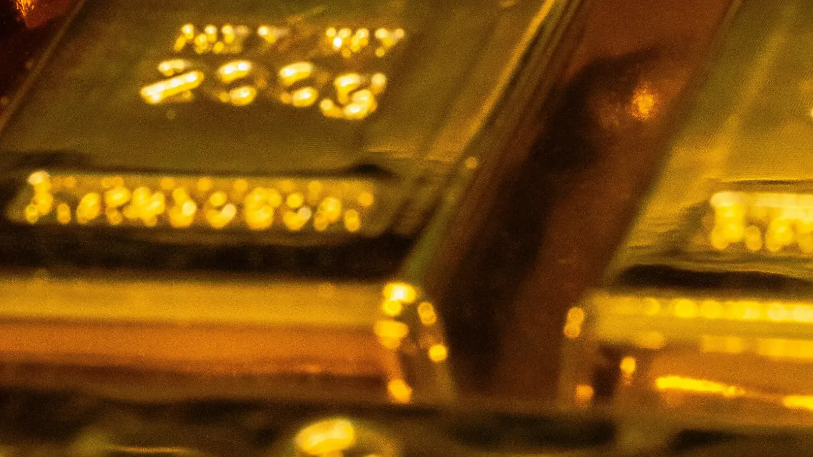 Macro of the stamped face of a cast gold bar, showing the assayer's mark and the '999.9 FINE GOLD' and net-weight lettering pressed into the metal