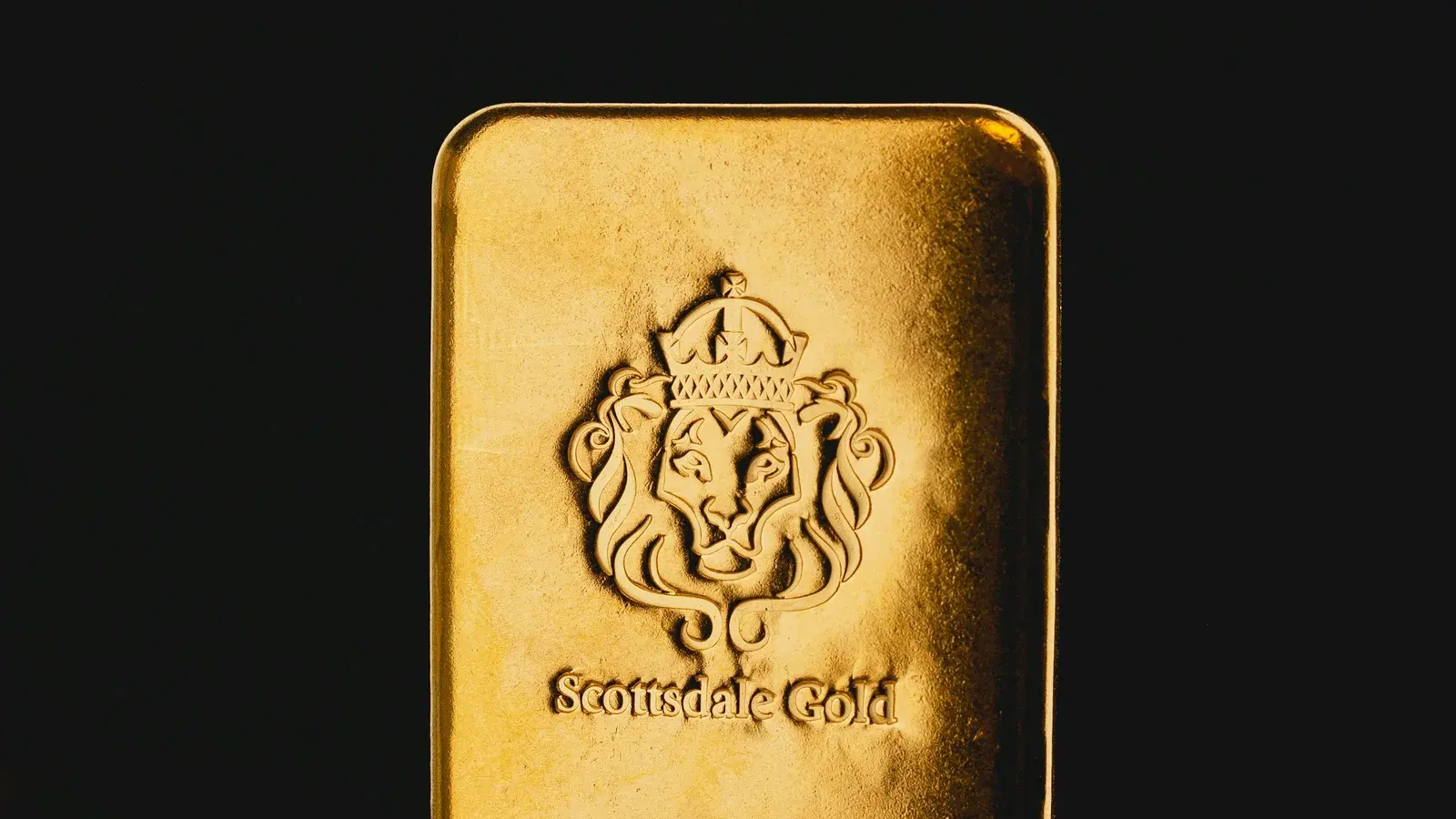 A poured gold bar struck with a crowned lion crest and the words Scottsdale Gold, against black