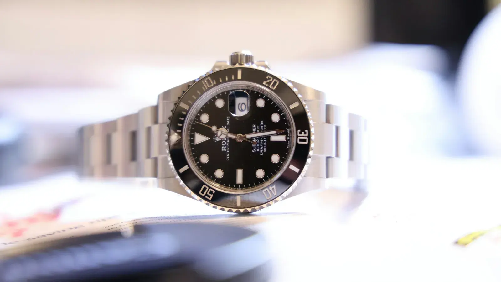 Stainless-steel Rolex Submariner Date with a black ceramic bezel and black dial, standing on its bracelet on a white table